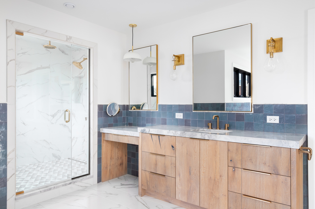 Blue tile double vanity bathroom with gold fixtures and marble shower